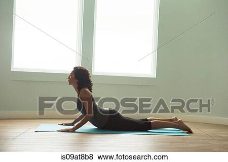Stock Photo - Mature woman lying on front practicing yoga. Fotosearch