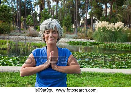 Mature woman meditating in park View Large Photo Image Stock Photograph - Mature woman meditating in park. Fotosearch