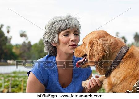 Picture - Mature woman petting dog, outdoors. Fotosearch
