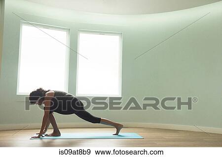 Stock Photo - Mature woman practicing yoga in curved room. Fotosearch