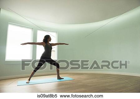 Stock Photography - Mature woman practicing yoga in curved room. Fotosearch