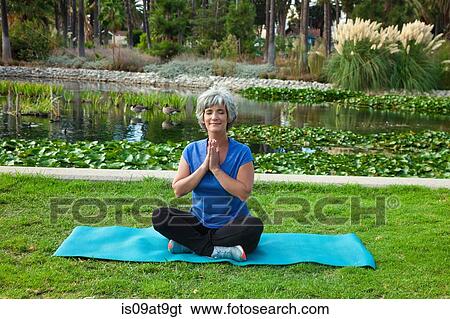 Mature woman sitting on mat in park, meditating View Large Photo Image Stock Photograph - Mature woman sitting on mat in park, meditating. Fotosearch
