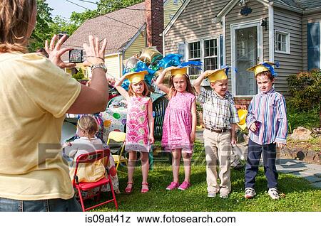 Mature woman taking photograph of children at kindergarten graduation View Large Photo Image Stock Photo - Mature woman taking photograph of children at kindergarten graduation. Fotosearch