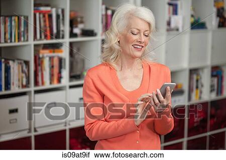 Mature woman using smartphone, indoors View Large Photo Image Stock Image - Mature woman using smartphone, indoors. Fotosearch
