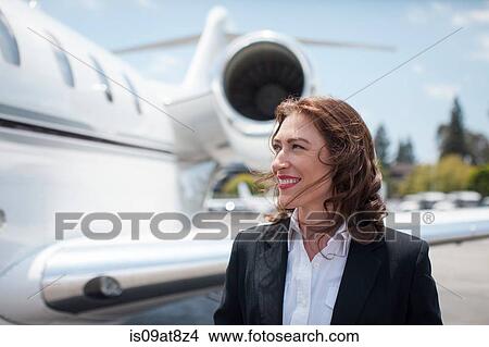 Picture - Mid adult female businesswoman and private jet at airport. Fotosearch