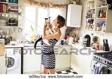 Mid adult woman carrying cat in kitchen View Large Photo Image Stock Photo - Mid adult woman carrying cat in kitchen. Fotosearch