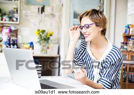 Mid adult woman online shopping in kitchen View Large Photo Image Stock Image - Mid adult woman online shopping in kitchen. Fotosearch