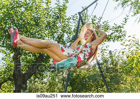 Mid adult woman swinging on garden swing, low angle view View Large Photo Image Stock Image - Mid adult woman swinging on garden swing, low angle view. Fotosearch