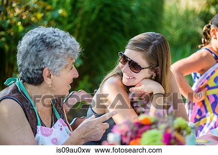 Stock Photo - Mid adult woman talking to senior woman in garden. Fotosearch