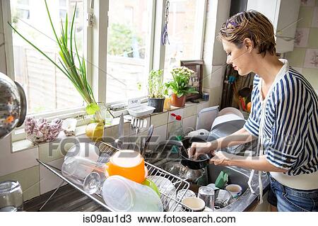 Mid adult woman washing up at kitchen sink View Large Photo Image Stock Image - Mid adult woman washing up at kitchen sink. Fotosearch