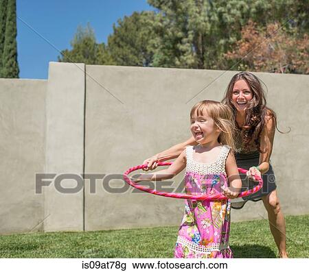 Mother and daughter playing with plastic hoop in garden View Large Photo Image Stock Image - Mother and daughter playing with plastic hoop in garden. Fotosearch