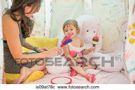 Mother and daughter sitting in play tent, playing with musical instruments View Large Photo Image Stock Image - Mother and daughter sitting in play tent, playing with musical instruments. Fotosearch