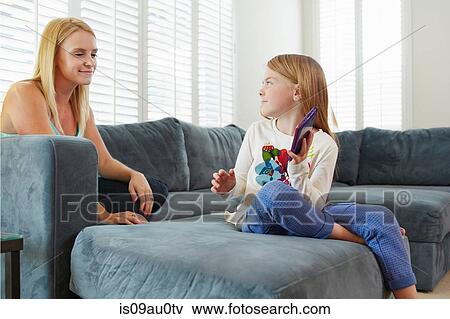 Stock Photo - Mother and daughter using digital tablet on sofa in living room. Fotosearch