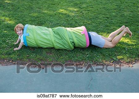 Stock Photo - Mother and son crawling through play tube in garden. Fotosearch