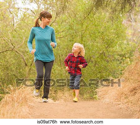Stock Image - Mother and son running in forest. Fotosearch