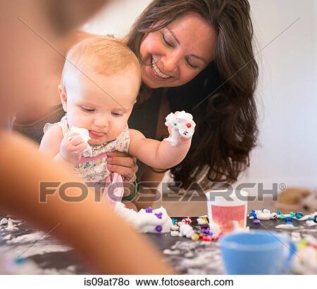 Mother holding baby girl while she plays View Large Photo Image Picture - Mother holding baby girl while she plays. Fotosearch