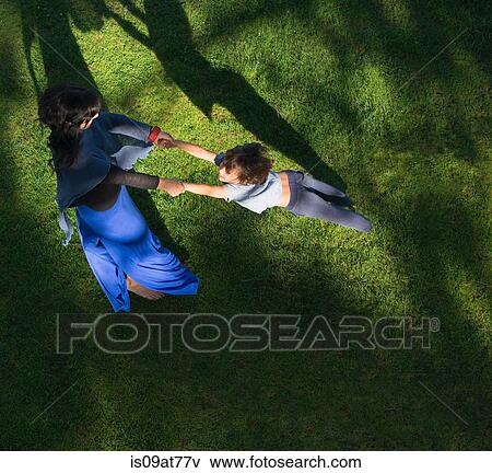 Stock Photo - Mother swinging son around, outdoors, elevated view. Fotosearch