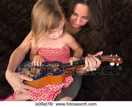 Mother teaching daughter to play the ukulele View Large Photo Image Stock Photography - Mother teaching daughter to play the ukulele. Fotosearch