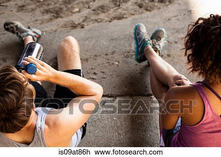 Stock Image - Overhead view of joggers taking break on kerb. Fotosearch