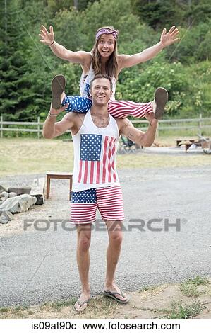 Stock Image - Portrait of couple wearing American flag costume celebrating Independence Day, USA. Fotosearch