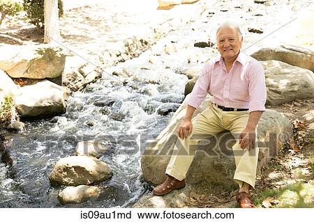 Portrait of senior man sitting on rock, outdoors View Large Photo Image Stock Image - Portrait of senior man sitting on rock, outdoors. Fotosearch