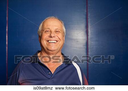 Stock Photo - Portrait of senior man (table tennis player) wearing navy blue polo shirt looking at camera smiling. Fotosearch