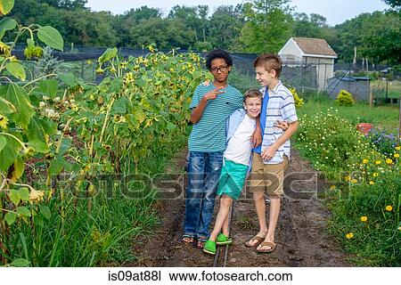 Stock Image - Portrait of three boys on field dirt track. Fotosearch