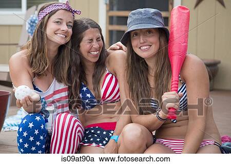 Stock Image - Portrait of three young women wearing American flag costume celebrating Independence Day, USA. Fotosearch
