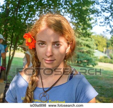 Stock Photo - Portrait of young woman with red flower in her hair. Fotosearch