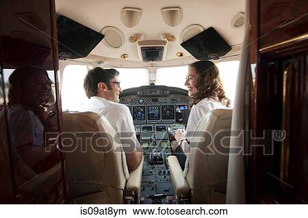 Rear view of male and female pilot chatting in cockpit of private jet View Large Photo Image Picture - Rear view of male and female pilot chatting in cockpit of private jet. Fotosearch
