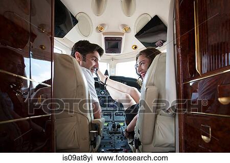 Rear view of male and female pilot with feet up in cockpit of private jet View Large Photo Image Stock Image - Rear view of male and female pilot with feet up in cockpit of private jet. Fotosearch