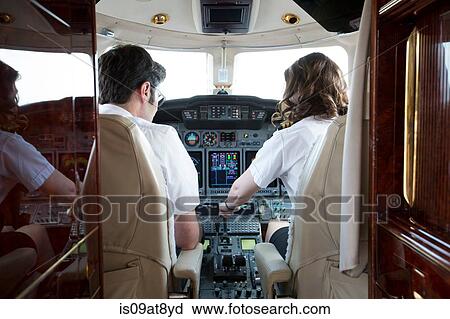 Rear view of male and female pilots in cockpit of private jet View Large Photo Image Stock Image - Rear view of male and female pilots in cockpit of private jet. Fotosearch