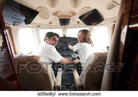 Rear view of male pilot with hand on womans knee in cockpit of private jet View Large Photo Image Stock Image - Rear view of male pilot with hand on womans knee in cockpit of private jet. Fotosearch