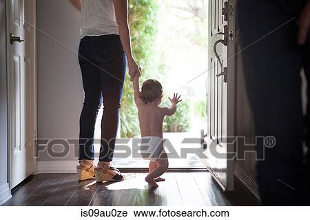 Rear view of mother holding baby boys hands standing at open front door View Large Photo Image Stock Image - Rear view of mother holding baby boys hands standing at open front door. Fotosearch