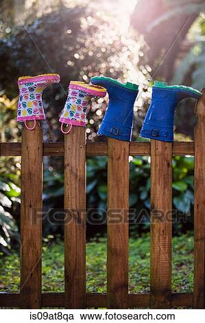 Stock Image - Rubber boots, upturned, on wooden fence posts. Fotosearch
