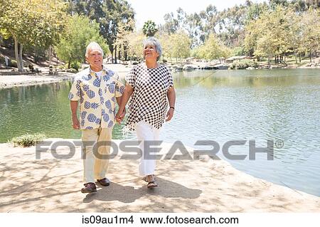 Senior couple walking hand in hand beside lake View Large Photo Image Picture - Senior couple walking hand in hand beside lake. Fotosearch