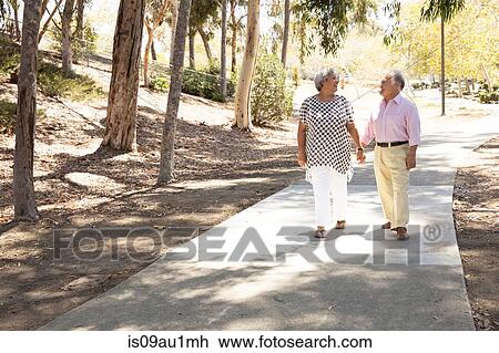 Stock Image - Senior couple walking hand in hand, outdoors. Fotosearch
