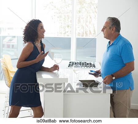 Senior man and wife chatting over kitchen counter View Large Photo Image Stock Image - Senior man and wife chatting over kitchen counter. Fotosearch