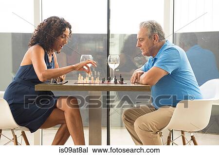 Stock Image - Senior man and wife playing chess. Fotosearch