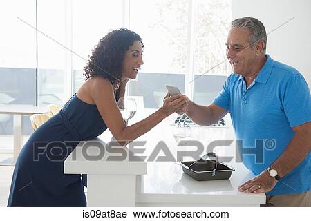 Senior man and wife reading smartphone texts over kitchen counter View Large Photo Image Stock Image - Senior man and wife reading smartphone texts over kitchen counter. Fotosearch