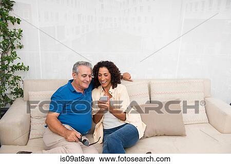 Senior man and wife reading smartphone texts on patio sofa View Large Photo Image Stock Photo - Senior man and wife reading smartphone texts on patio sofa. Fotosearch