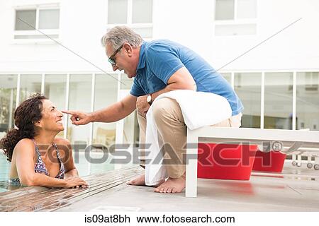 Stock Image - Senior man touching wifes nose from poolside. Fotosearch