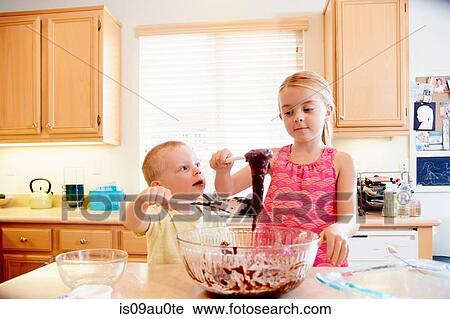Stock Image - Siblings melting chocolate in mixing bowl. Fotosearch