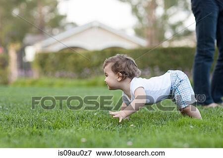 Stock Photo - Side view of baby boy crawling on grass. Fotosearch