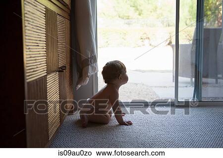 Side view of baby boy sitting in front of patio doors, looking away View Large Photo Image Picture - Side view of baby boy sitting in front of patio doors, looking away. Fotosearch