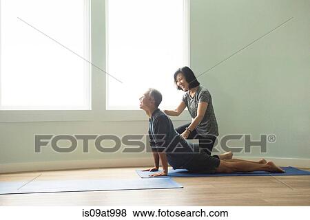 Side view of mature couple doing yoga push up, correcting posture View Large Photo Image Stock Photo - Side view of mature couple doing yoga push up, correcting posture. Fotosearch