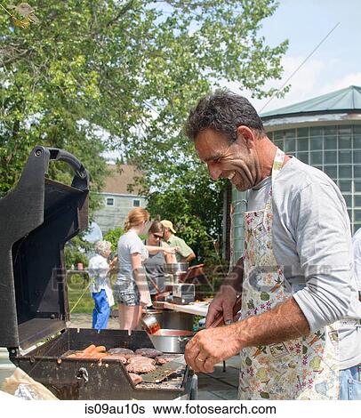 Side view of mature man cooking for family on barbecue looking down smiling View Large Photo Image Stock Photograph - Side view of mature man cooking for family on barbecue looking down smiling. Fotosearch