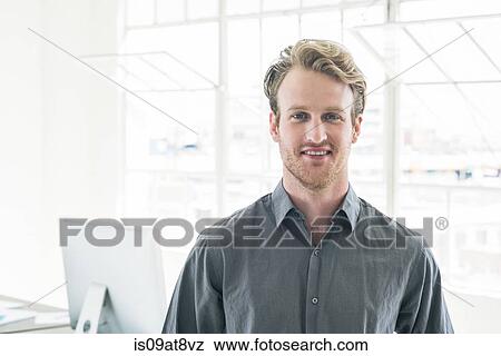 Stock Photo - Smiling businessman by office window. Fotosearch