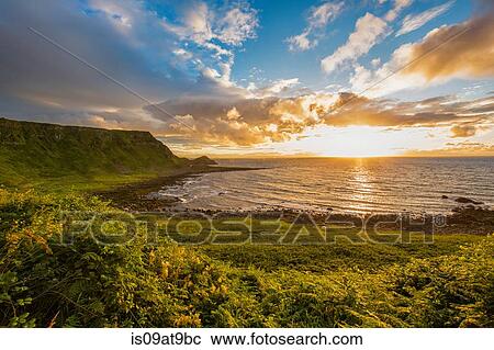 Sun setting on horizon over ocean, Giants Causeway, Bushmills, County Antrim, Ireland, UK View Large Photo Image Stock Image - Sun setting on horizon over ocean, Giants Causeway, Bushmills, County Antrim, Ireland, UK. Fotosearch