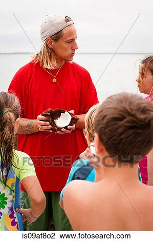 Stock Image - Teacher holding coconut, teaching children, Sanibel Island, Pine Island Sound, Florida, USA. Fotosearch